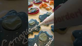 Cookie artist is piping the word Congrats on graduation cookies [upl. by Gilberta]